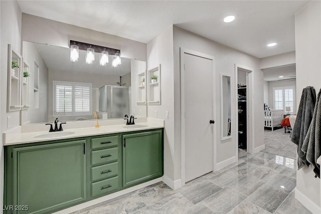 full bath with double vanity, a stall shower, baseboards, and a sink