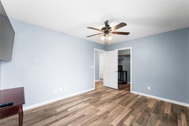 unfurnished bedroom with a closet, baseboards, wood finished floors, and a ceiling fan