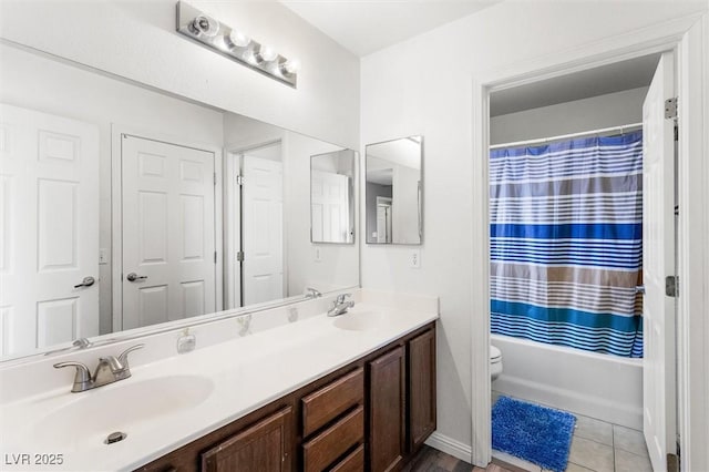 full bath featuring tile patterned floors, double vanity, toilet, and a sink