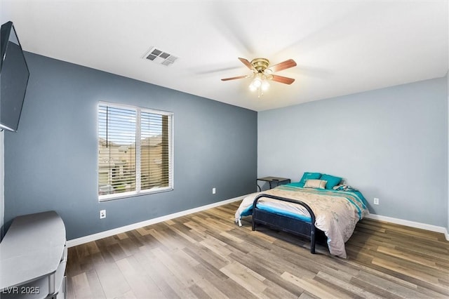 bedroom featuring ceiling fan, wood finished floors, visible vents, and baseboards