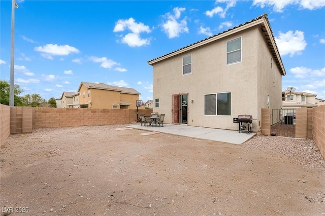 rear view of house featuring stucco siding, a patio, and a fenced backyard