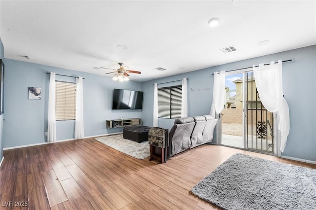 living area featuring visible vents, baseboards, ceiling fan, and wood finished floors