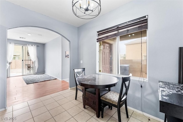 dining room featuring baseboards, visible vents, arched walkways, tile patterned floors, and a chandelier