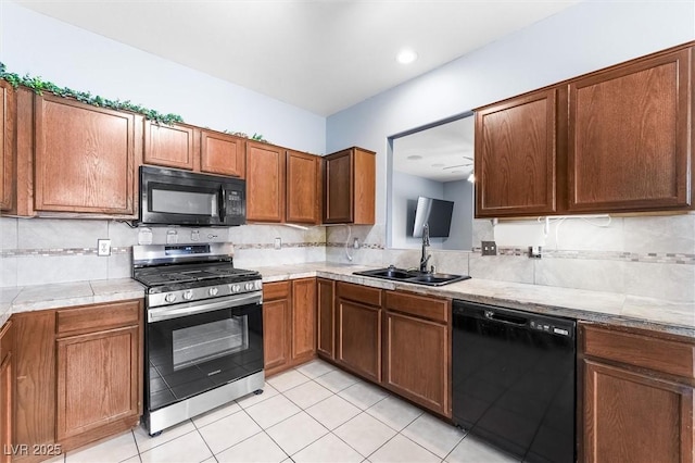 kitchen featuring light tile patterned floors, backsplash, black appliances, and a sink