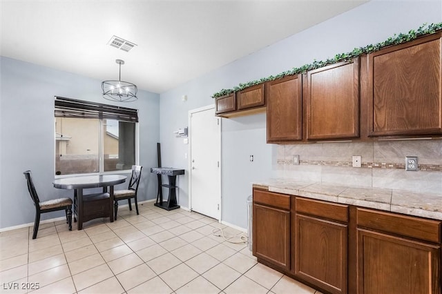 kitchen featuring visible vents, backsplash, hanging light fixtures, and light countertops