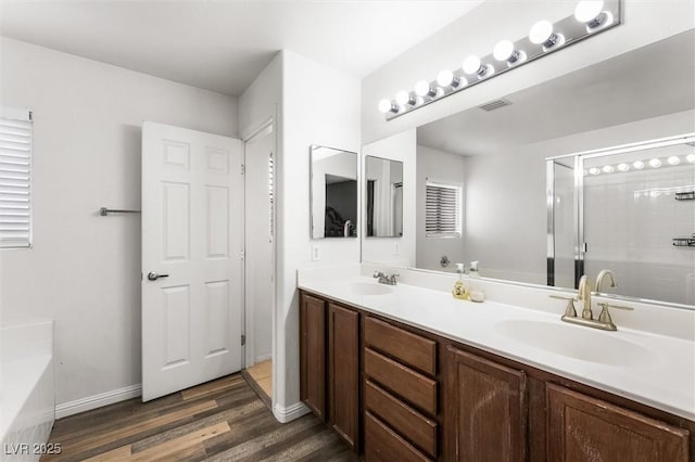 full bath featuring double vanity, a shower stall, wood finished floors, and a sink