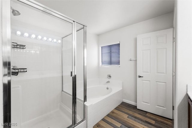 bathroom featuring a stall shower, vanity, a garden tub, and wood finished floors