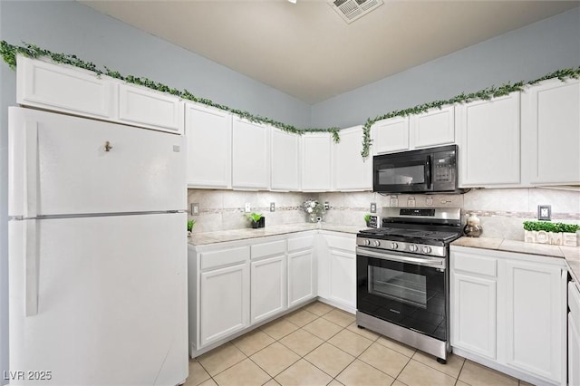6429 Pronghorn Ridge Ave, Las Vegas, NV 89122 - kitchen with freestanding refrigerator, black microwave, stainless steel range with gas stovetop, and white cabinetry