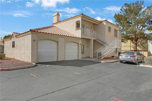 view of front of home with aphalt driveway, stucco siding, an attached garage, and stairs