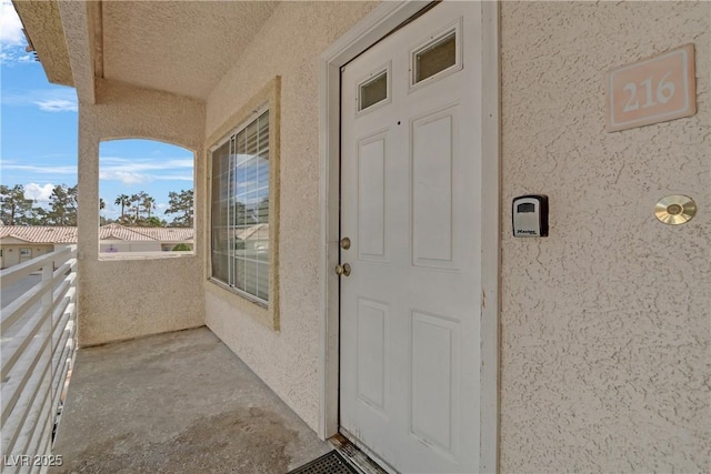 entrance to property featuring stucco siding and a balcony