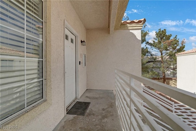 view of exterior entry featuring stucco siding, a balcony, and a tiled roof