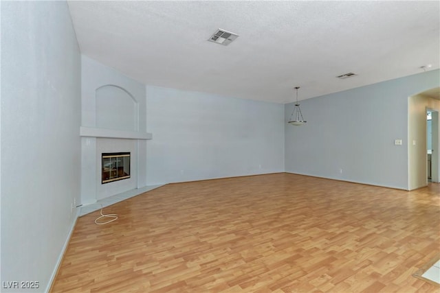 unfurnished living room with visible vents, light wood-type flooring, and a fireplace with flush hearth