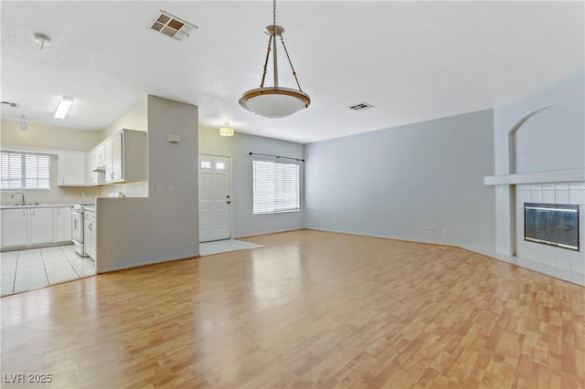 unfurnished living room featuring visible vents, plenty of natural light, and a sink