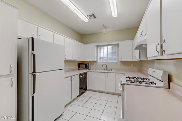 kitchen featuring under cabinet range hood, light countertops, light tile patterned floors, white appliances, and a sink