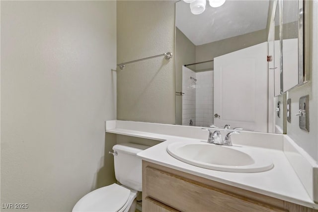 full bath featuring toilet, vanity, walk in shower, and a textured wall