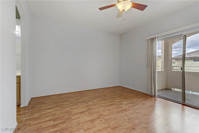 spare room with arched walkways, light wood-style floors, and ceiling fan