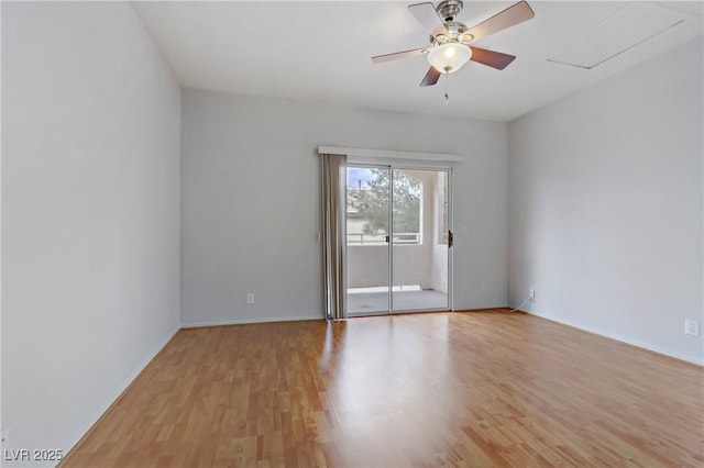 empty room featuring attic access, light wood-style floors, and a ceiling fan