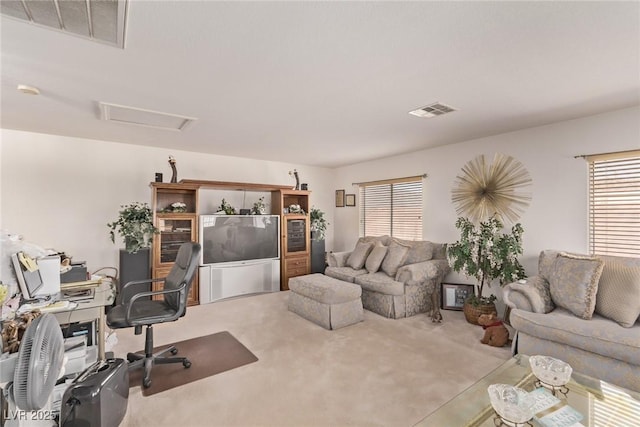 carpeted living area featuring visible vents, attic access, and a wealth of natural light