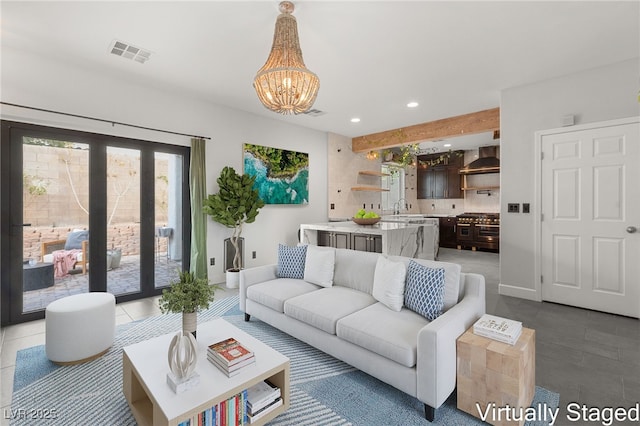 tiled living room with visible vents, a sink, recessed lighting, an inviting chandelier, and baseboards