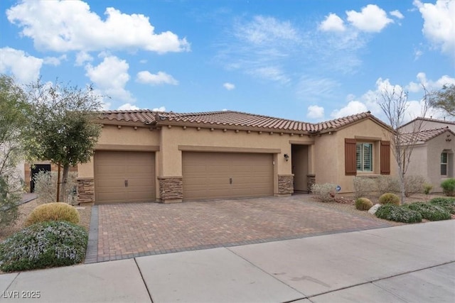 mediterranean / spanish-style home with decorative driveway, stucco siding, an attached garage, and a tiled roof