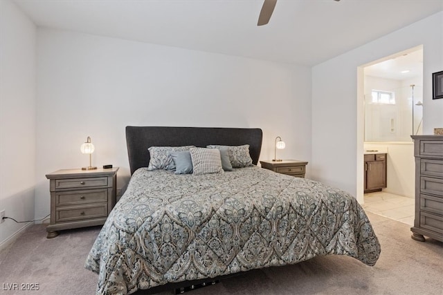 bedroom with a ceiling fan, light colored carpet, and ensuite bathroom