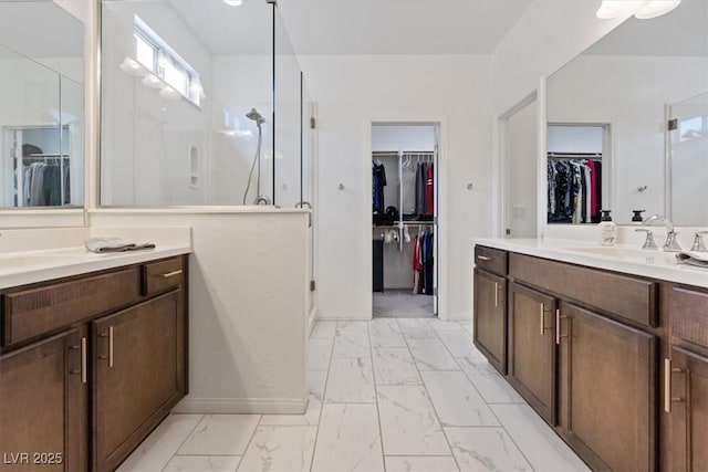 bathroom with a walk in closet, two vanities, a stall shower, marble finish floor, and a sink