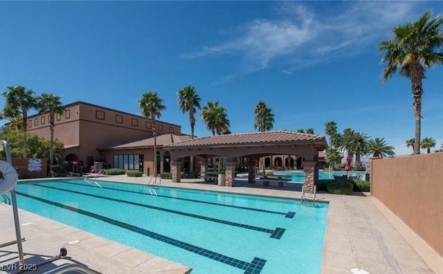 community pool with a patio area and fence