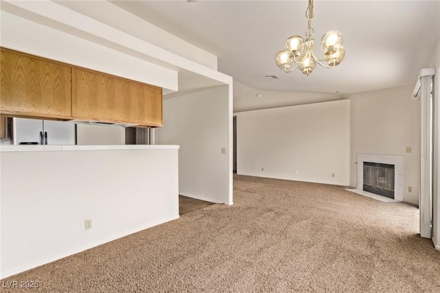 unfurnished living room featuring an inviting chandelier, carpet flooring, lofted ceiling, and a tile fireplace