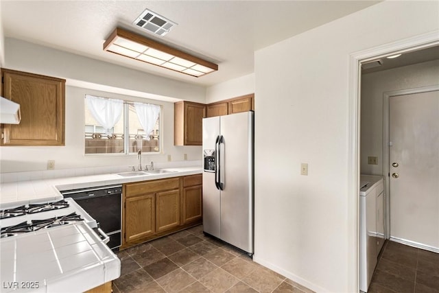 kitchen with tile countertops, visible vents, a sink, washer and dryer, and stainless steel fridge