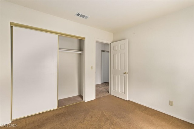 unfurnished bedroom with visible vents, a closet, and carpet flooring