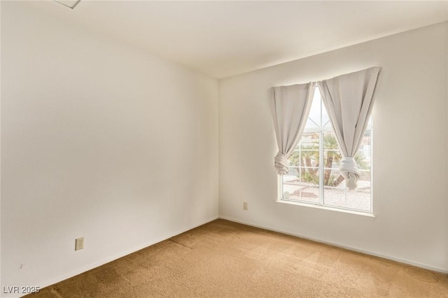 empty room featuring light colored carpet and baseboards