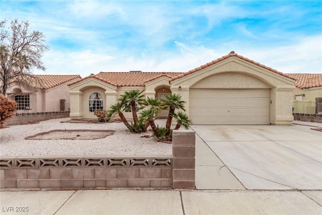 mediterranean / spanish-style house with stucco siding, driveway, a tile roof, fence, and an attached garage