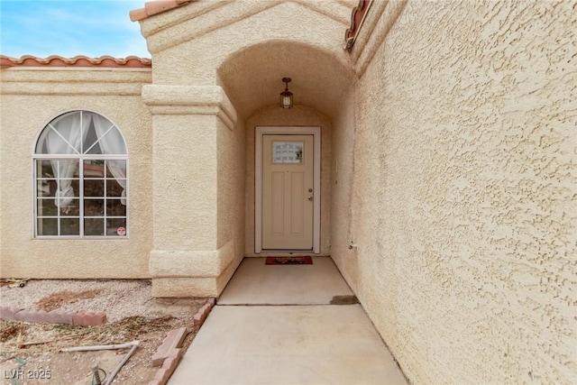 property entrance with stucco siding and a tiled roof