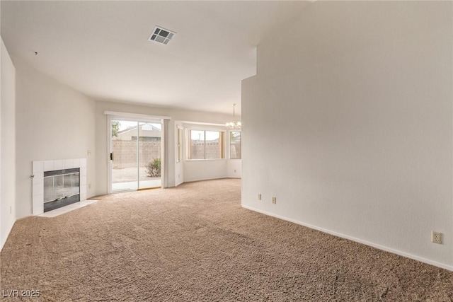 unfurnished living room with visible vents, a notable chandelier, a fireplace, carpet flooring, and baseboards