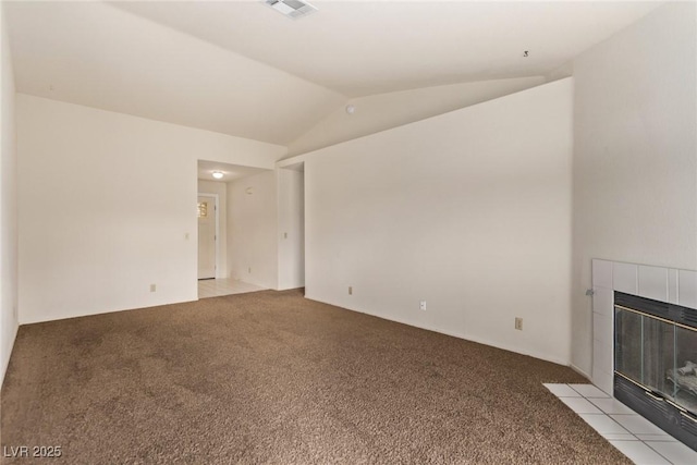 unfurnished living room with a tiled fireplace, vaulted ceiling, visible vents, and light carpet