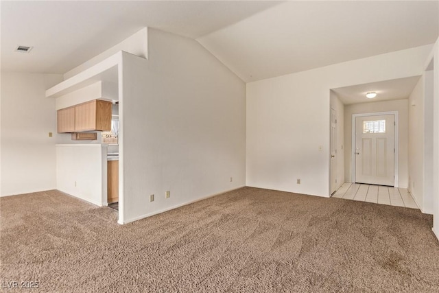 unfurnished living room featuring light carpet, visible vents, and vaulted ceiling