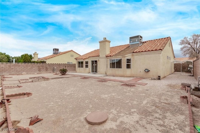 rear view of property featuring a tiled roof, stucco siding, cooling unit, a fenced backyard, and a patio area