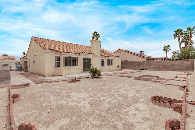 rear view of property with a fenced backyard, stucco siding, a tiled roof, and a patio