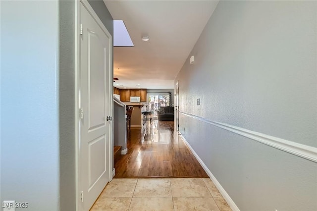 corridor featuring light tile patterned floors and baseboards