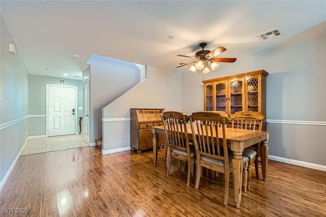 dining room with a ceiling fan, wood finished floors, visible vents, and baseboards