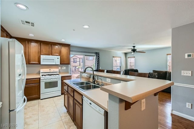 kitchen with visible vents, a sink, open floor plan, white appliances, and light countertops