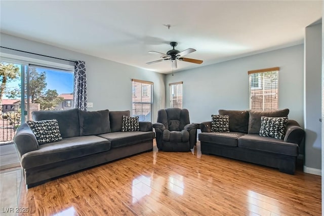 living area with baseboards, wood finished floors, and a ceiling fan