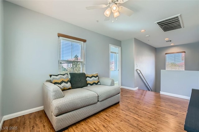 living area featuring visible vents, baseboards, a healthy amount of sunlight, and wood finished floors