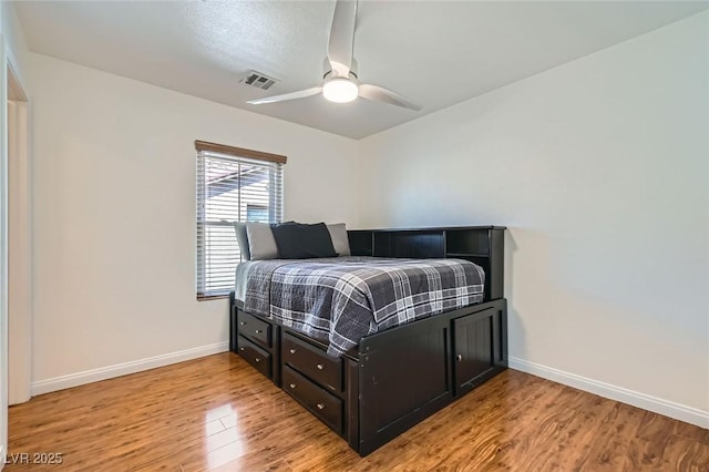 bedroom with a ceiling fan, baseboards, visible vents, and light wood finished floors