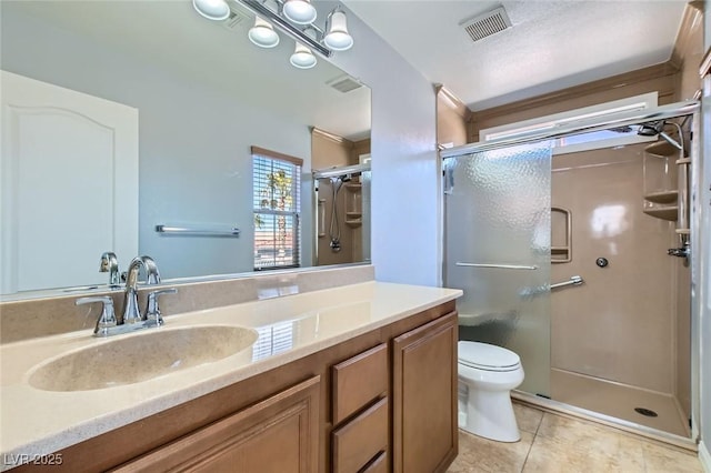 bathroom featuring toilet, a stall shower, vanity, and tile patterned flooring