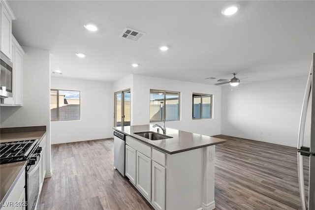 kitchen featuring dark wood-style floors, visible vents, a sink, appliances with stainless steel finishes, and dark countertops