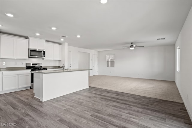 kitchen featuring visible vents, stainless steel appliances, ceiling fan, and wood finished floors