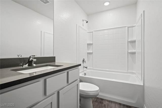 bathroom featuring vanity, wood finished floors, visible vents, bathtub / shower combination, and toilet