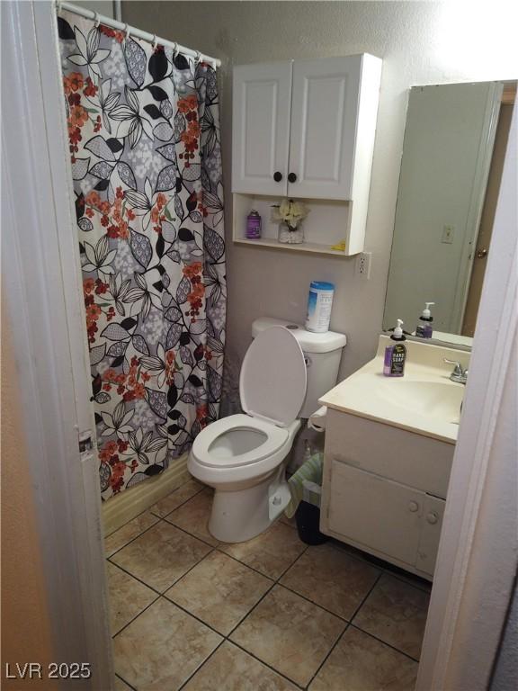 full bath featuring curtained shower, toilet, vanity, and tile patterned flooring