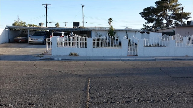 view of front of house with a fenced front yard, covered parking, and stucco siding